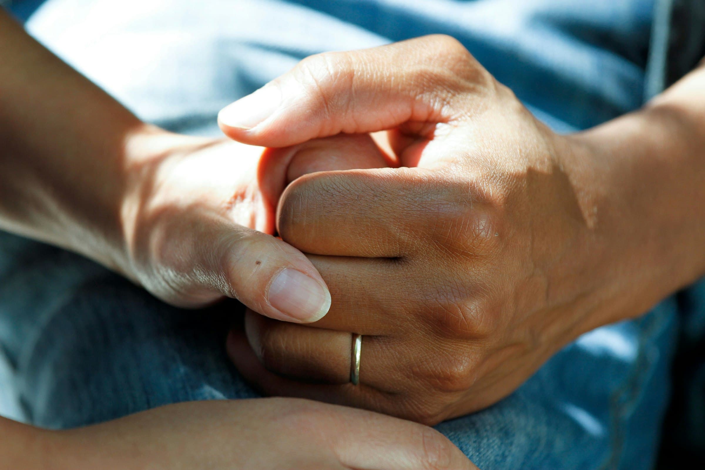 Two hands clasped together in comfort, a symbol of the love at the heart of caregiving